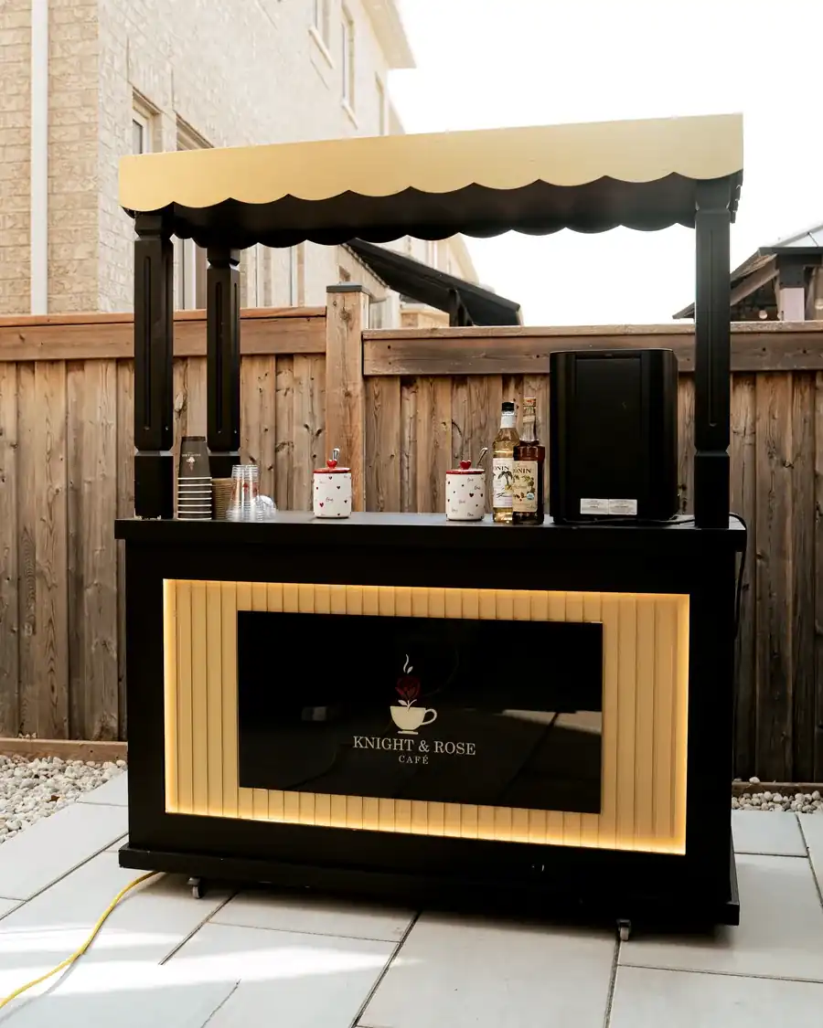 The Knight & Rose mobile café cart in black and gold, set up outdoors for an event.