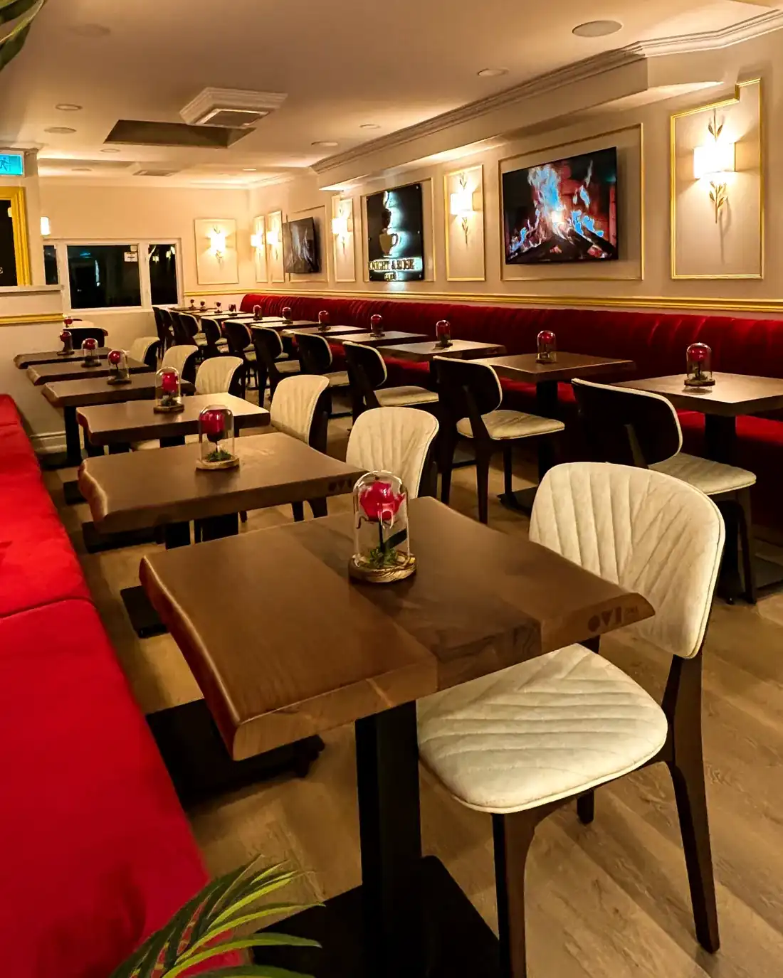 Walnut tables and red velvet banquettes at Knight & Rose Café, each set with a rose under glass.