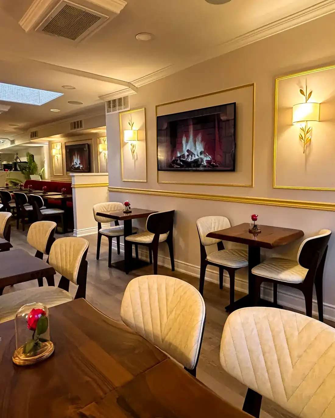 The corner of the Knight & Rose dining room with banquettes, walnut tables and gold sconces.
